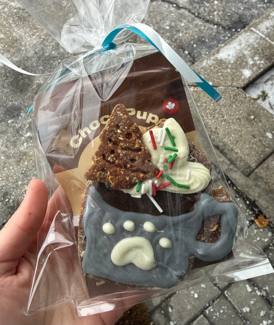 Hot Chocolate cookie with a paw print design, and dog safe hot chocolate pack held in a clear plastic bag.
