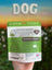 Hand holding a package of Venison Crisps for dogs with a blurred outdoor background
