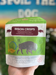 Packaged bison crisps held in a hand with a blurred background