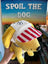 Yellow plush dog toy with a red and white striped hat held in front of a sign.