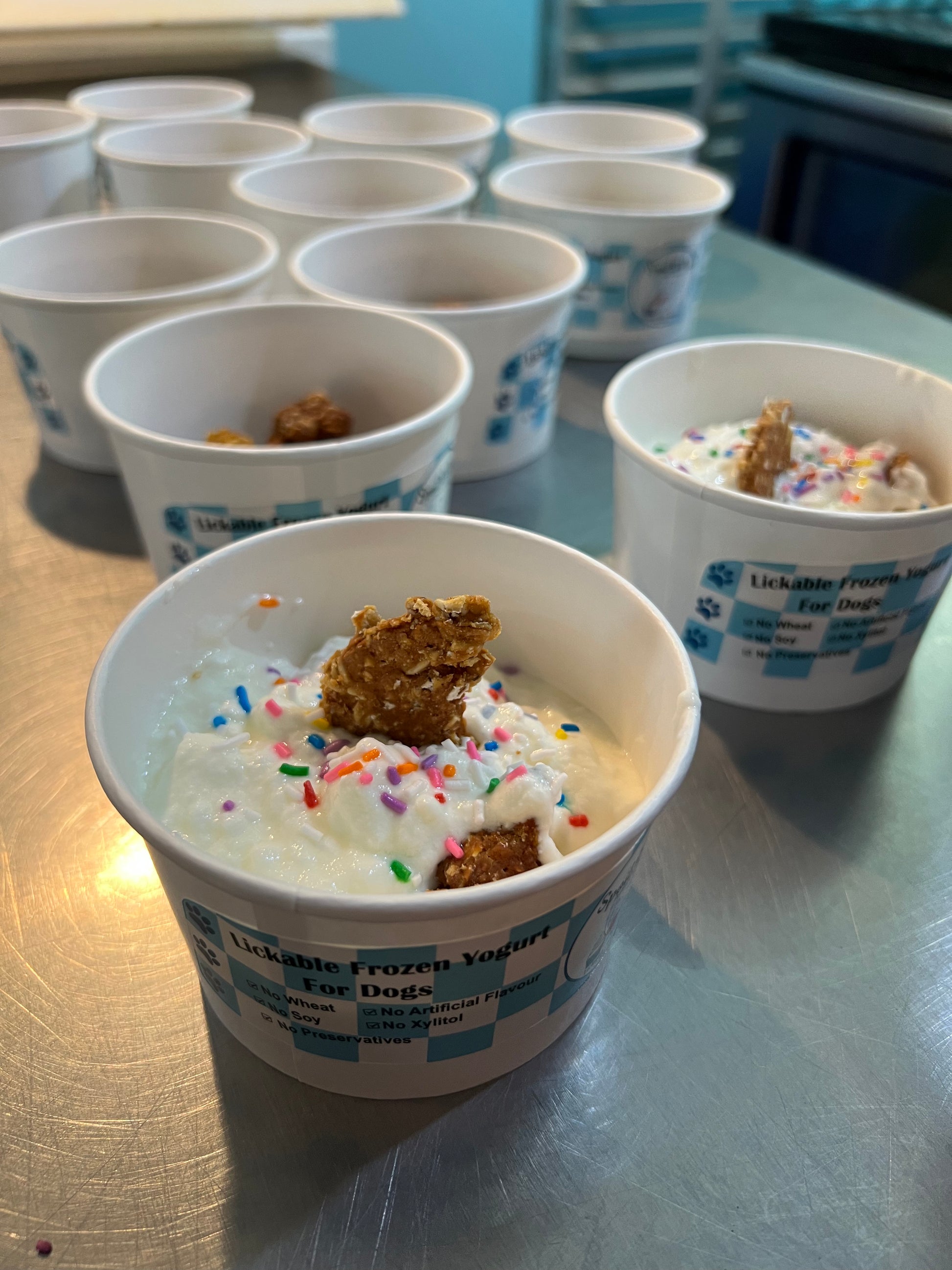 Ice cream cups with sprinkles and cookie pieces on a kitchen island.