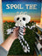 Hand holding a dog toy with a skeleton design and rope, with 'Spoil the Dog' sign in the background.