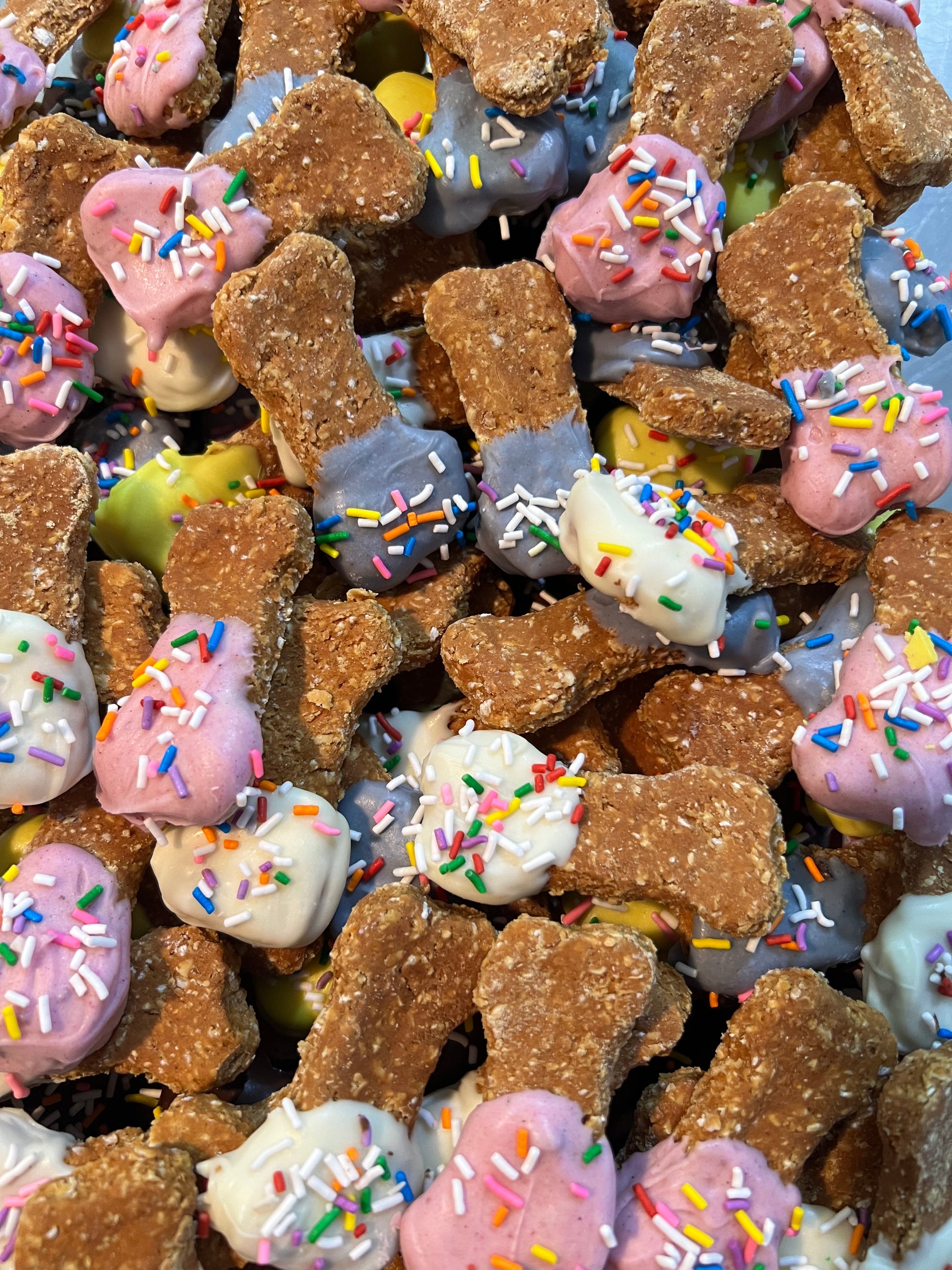 Dog treats shaped like bones with colorful sprinkles on a pile.