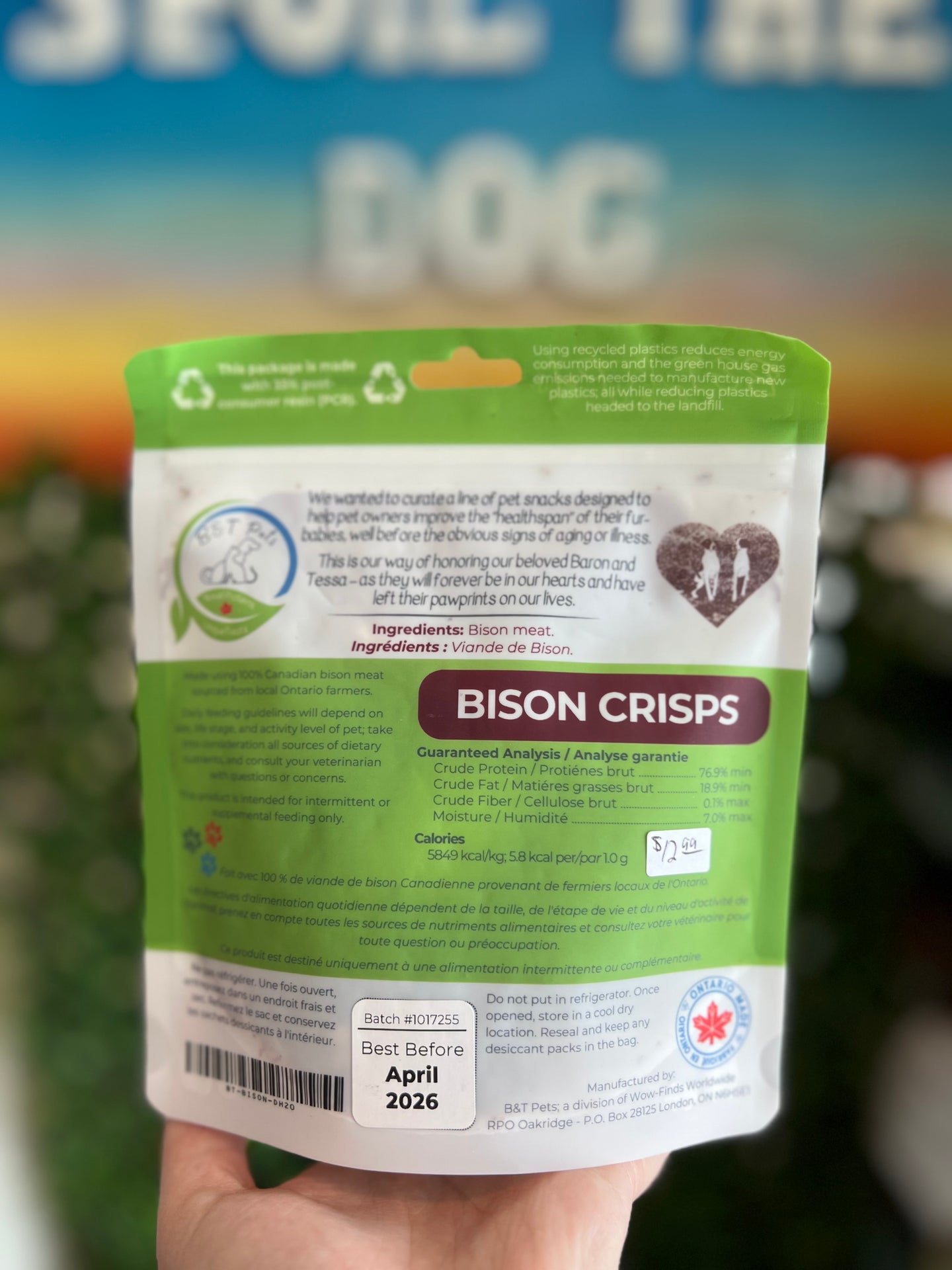 Hand holding a package of Bison Crisps with a blurred outdoor background