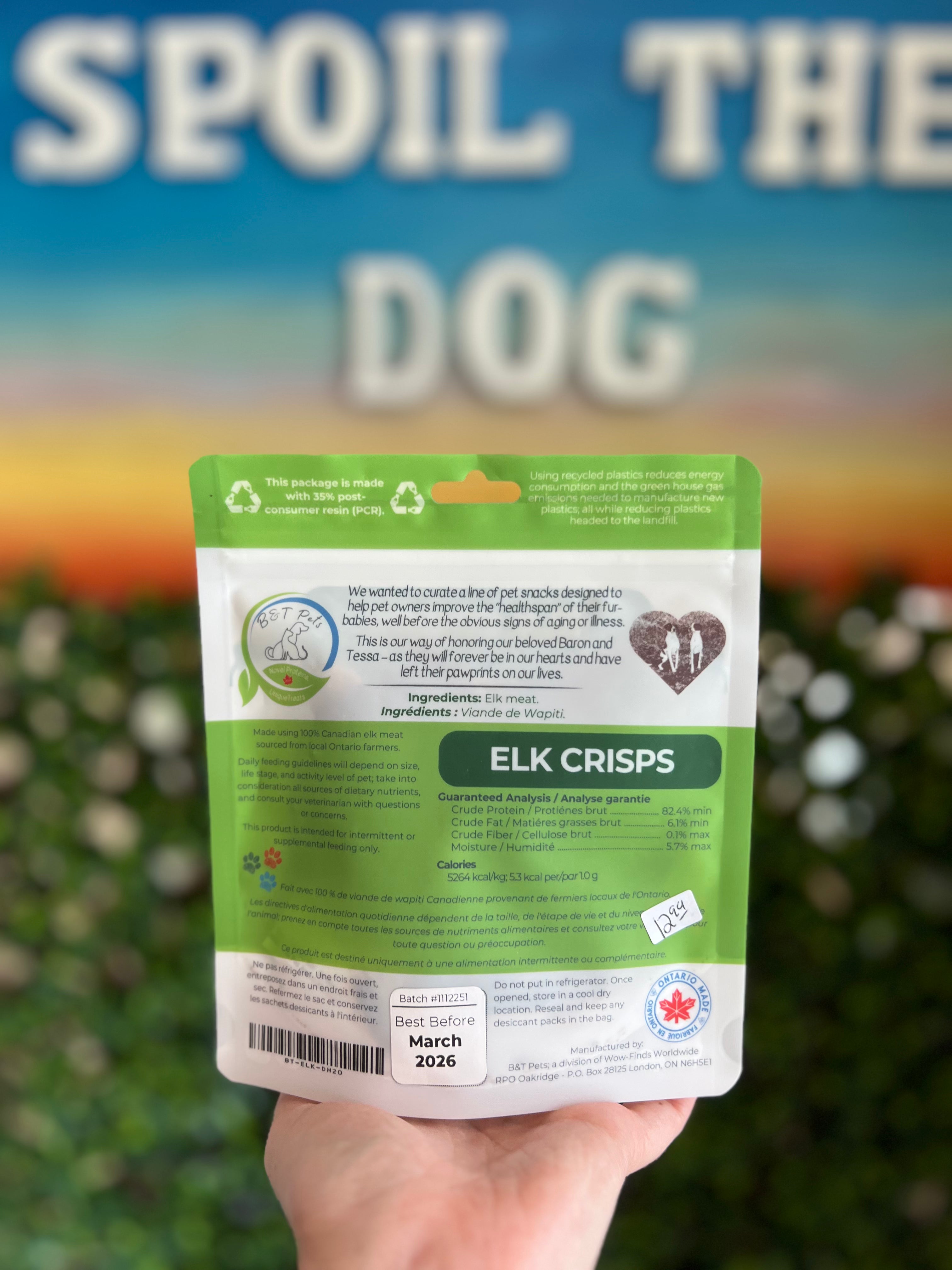 Hand holding a package of 'Elk Crisps' with a blurred background and text.