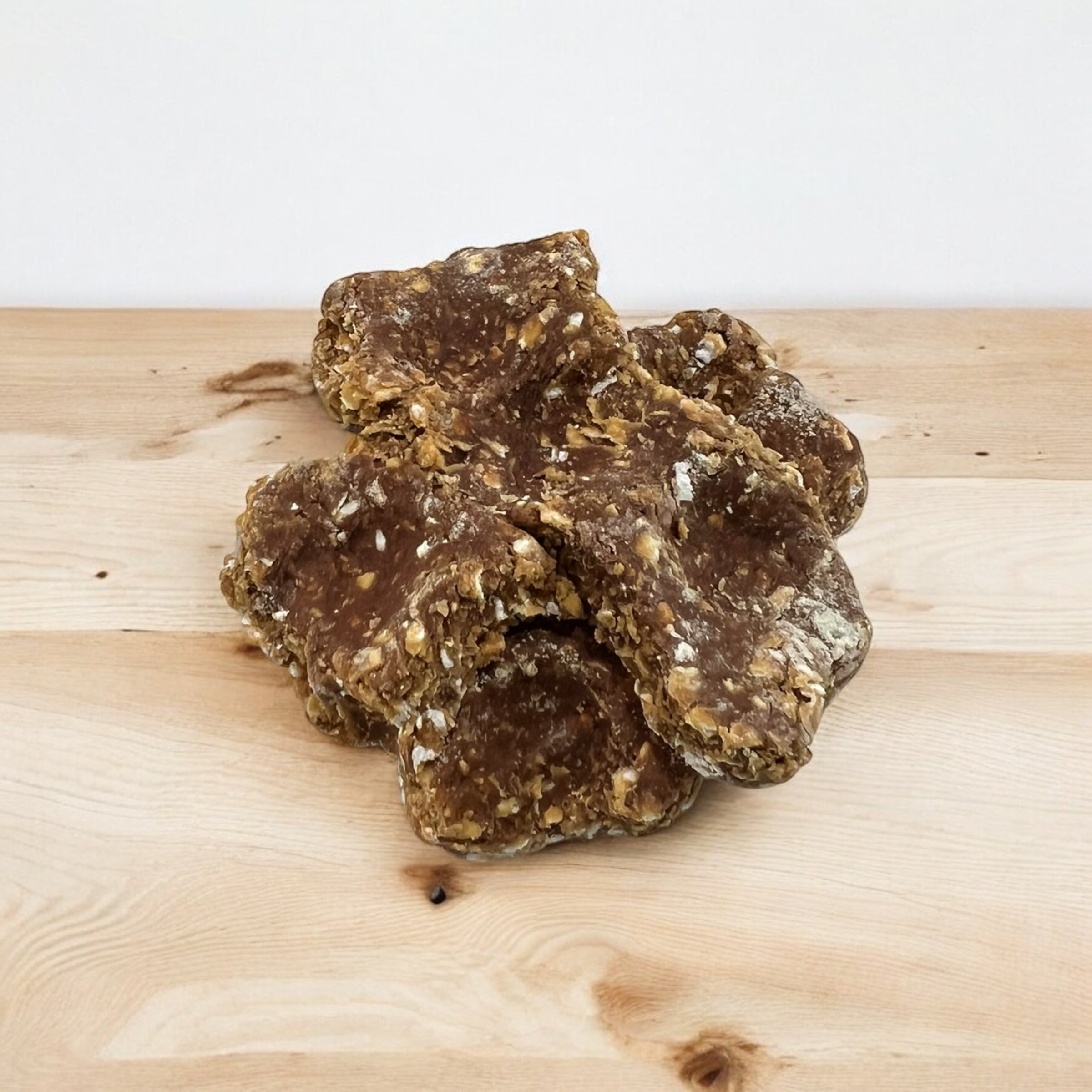 A dog treat made of apple, coconut, and other ingredients, presented on a wooden surface.
