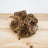 A dog treat made of apple, coconut, and other ingredients, presented on a wooden surface.