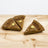 Three triangular pumpkin pie dog treats on a wooden surface.