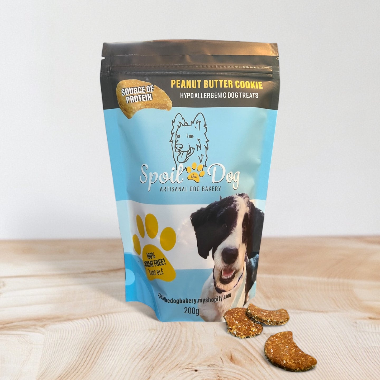 A pack of Spoil the Dog brand wheat-free peanut butter flavored dog treats. The packaging is blue with an image of a dog and the treats are visible in front of the pack.
