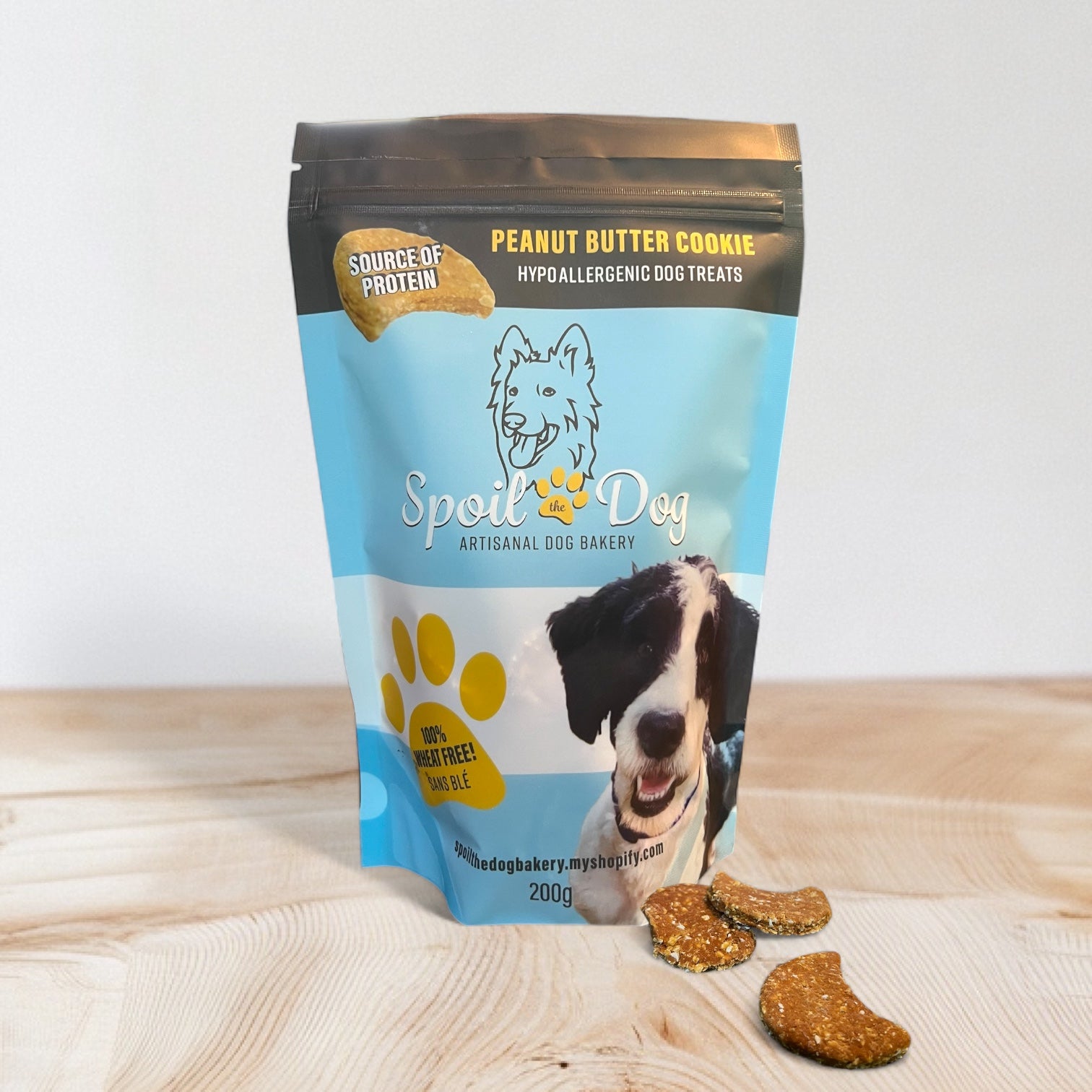 A pack of Spoil the Dog brand wheat-free peanut butter flavored dog treats. The packaging is blue with an image of a dog and the treats are visible in front of the pack.