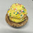 Yellow dog cupcake with sprinkles on a wooden surface.