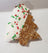 Tree shaped dog cookie half dipped in white yogurt, with sprinkles.