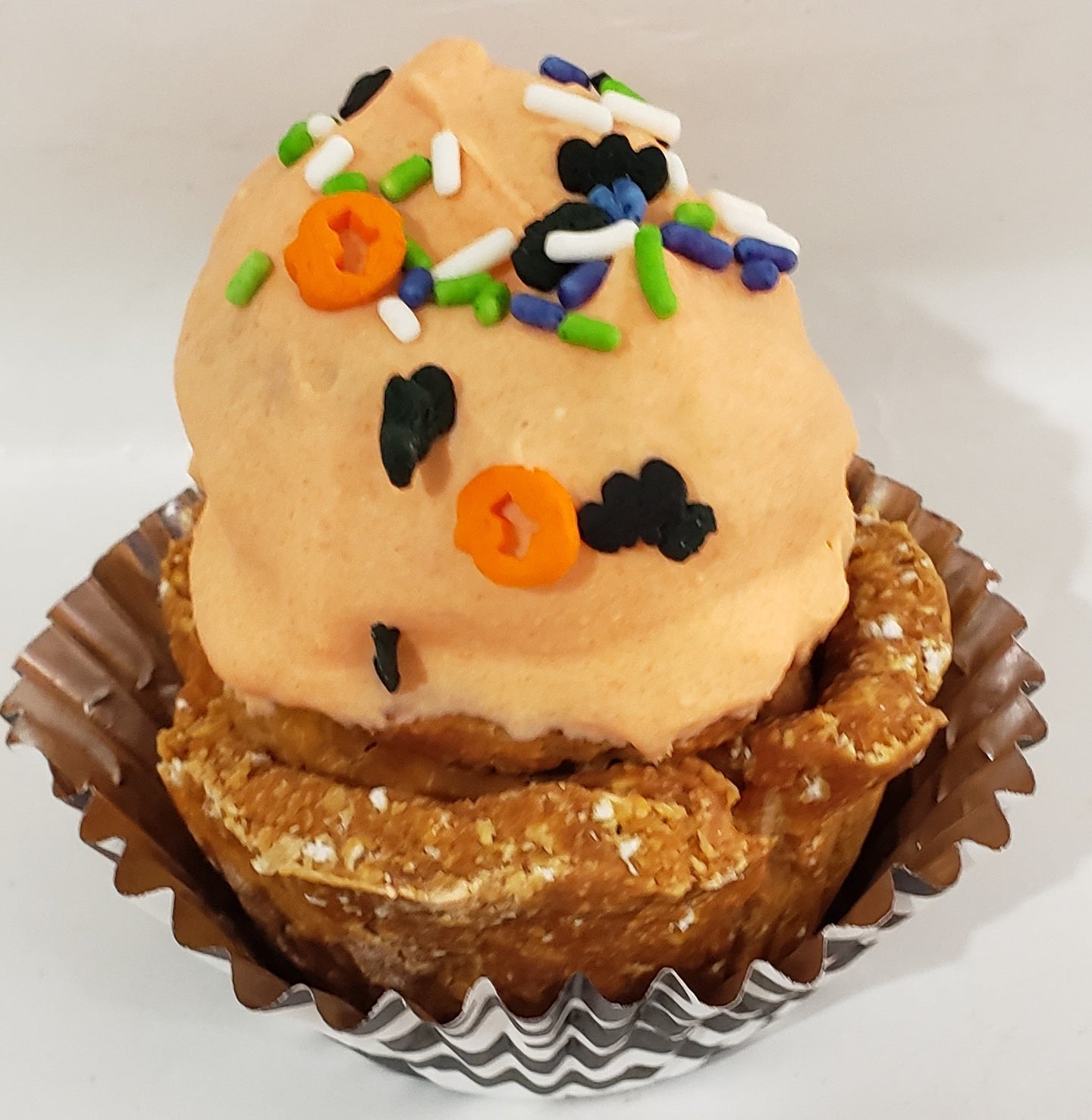 Orange dog cupcakes with sprinkles on a wooden surface.