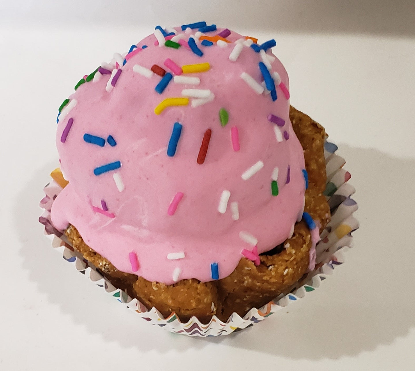 Pink dog cupcakes with sprinkles on a wooden surface.