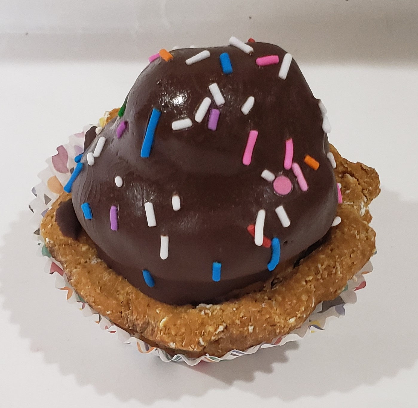 Chocolate colour dog cupcake with sprinkles on a wooden surface. Icing is made from carob.