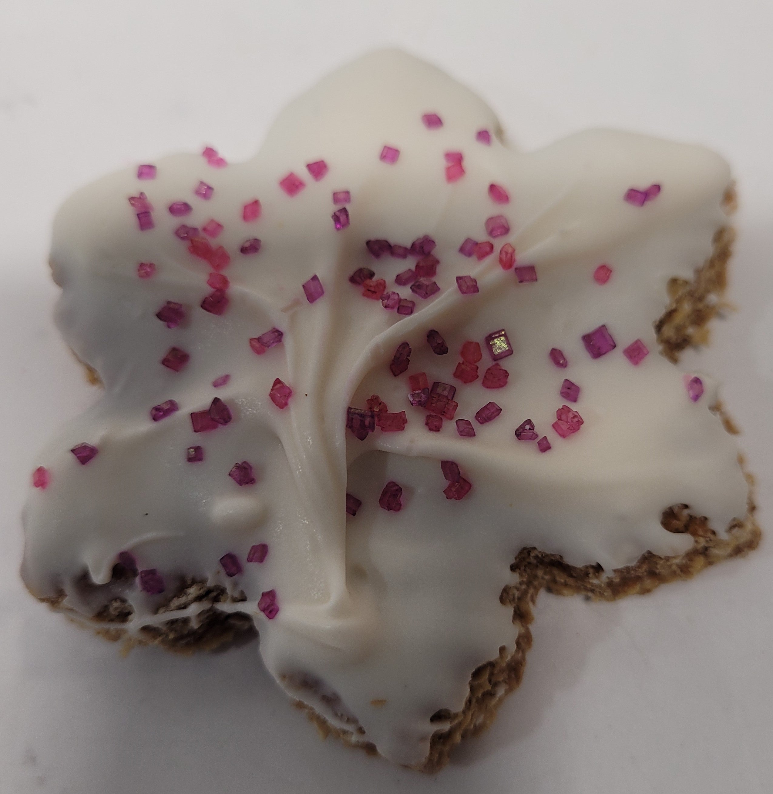 Snowflake dog cookie with purple sprinkles on a white background