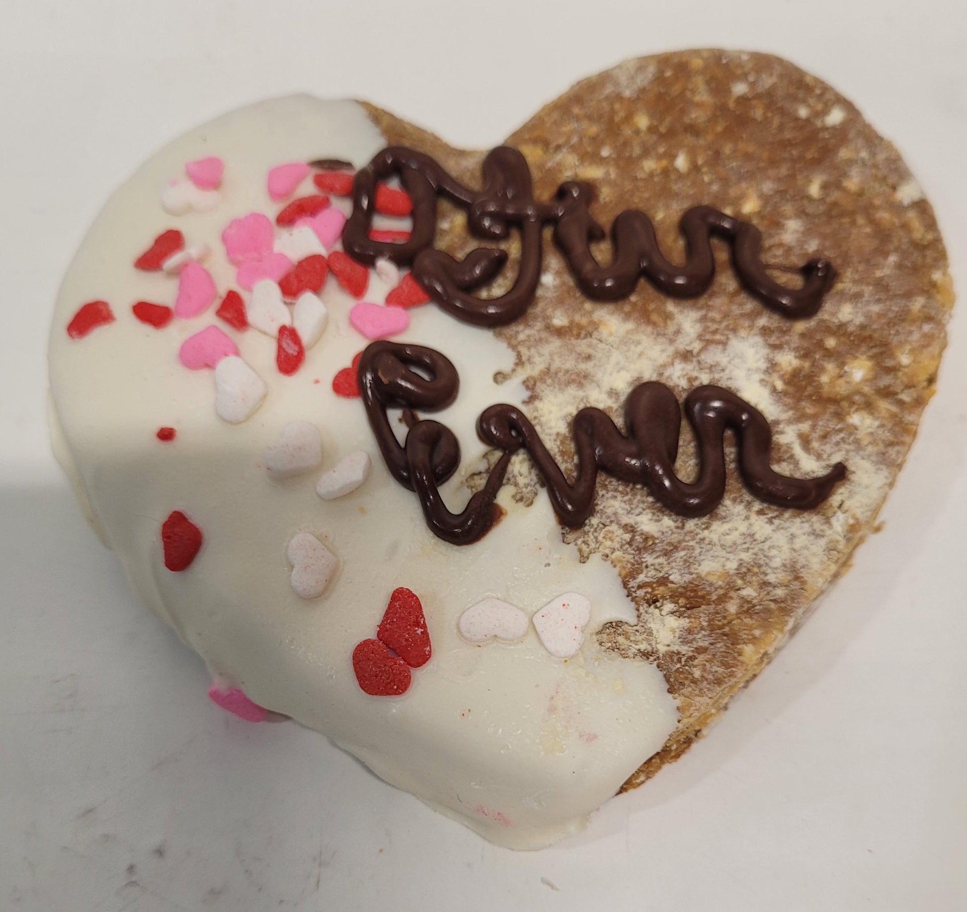 Heart shaped cookie dipped in white yogurt, with the word "Furever" piped in carob